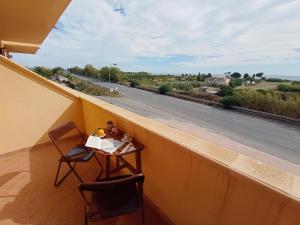 balcón con mesa, sillas y carretera en Degli Angioini Holiday Home, en Caulonia Marina