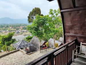 a balcony with a view of a river and trees at Arafah Resort @ Danau Kerinci Jambi RedPartner in Hiang