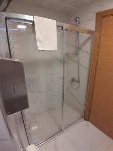 La salle de bains est pourvue d'une douche avec une porte en verre. dans l'établissement Del Puerto Hotel, à Aliağa