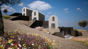 une séance d'une maison sur une colline avec des fleurs dans l'établissement Bay View Residences Santorini, à Akrotiri