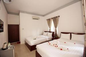una habitación de hotel con 2 camas con flores. en Nu Cuoi Mui Ne Hotel & Restaurant, en Phan Thiet