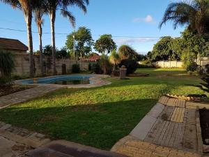 a yard with a swimming pool and palm trees at Emangweni Guest House in Vryheid