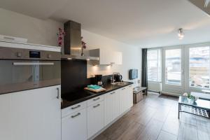 a kitchen with white cabinets and a large window at SummerTime Bergen aan Zee in Bergen aan Zee