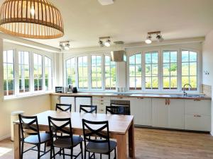 a kitchen with a wooden table and chairs and windows at L'Altenberg in Bergheim