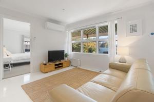 een witte woonkamer met een bank en een tv bij Sea View Cottage Escape in Middleton