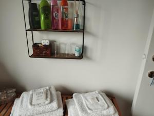 uma casa de banho com duas toalhas brancas numa prateleira em Logies Lily em Oudenburg