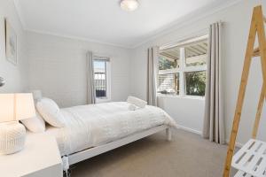 een witte slaapkamer met een bed en een raam bij Sea View Cottage Escape in Middleton