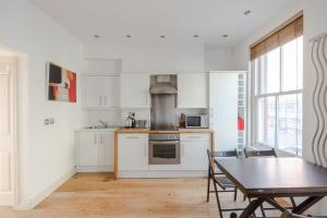 uma cozinha com armários brancos, uma mesa e uma sala de jantar em The Play Pen - Holborn - by Frankie Says em Londres