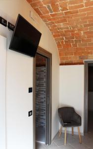 einen Stuhl neben einer Wand mit einem Flachbild-TV in der Unterkunft LA LOCANDA DA VITTORIO in Sassa