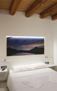 ein Schlafzimmer mit einem weißen Bett und einem Gemälde an der Wand in der Unterkunft LA LOCANDA DA VITTORIO in Sassa