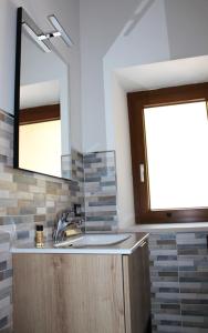 ein Bad mit einem Waschbecken und einem Spiegel in der Unterkunft LA LOCANDA DA VITTORIO in Sassa