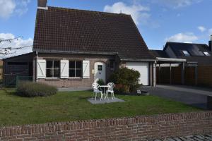 uma casa com duas cadeiras brancas em frente em Rust aan de kust em Middelkerke