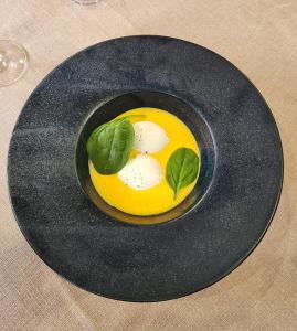 a black plate with an egg on a table at LOGIS Hôtel & Restaurant Le Soleil D'or in Montigny-la-Resle