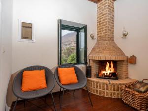 two chairs with orange pillows sitting in front of a fireplace at Ornus Traditional House in Orné