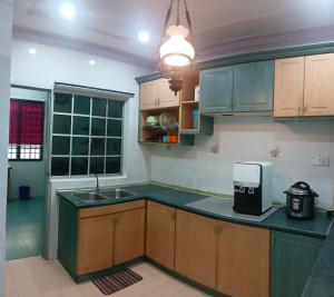 a kitchen with green cabinets and a sink and a counter top at Homestay No. 8 in Segamat