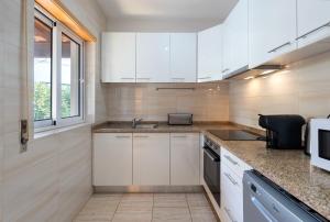 uma cozinha com armários brancos e um lavatório em ALTIDO Warm and Inviting flat with balcony no Porto