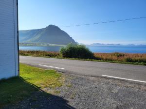 an empty road next to the ocean with a mountain at Nøss Panorama in Nøss