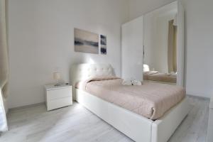 a white bedroom with a bed and a mirror at Orsini Luxury Apartment in Florence