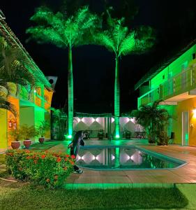 a pool in a courtyard with palm trees at night at Pousada Maturi - Pipa in Pipa