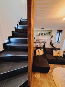 ein Wohnzimmer mit einem Sofa und einer Treppe in der Unterkunft Gîte Chez Nénene La Roche en Ardenne in La-Roche-en-Ardenne
