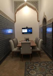 uma sala de jantar com mesa e cadeiras e uma televisão em Dar Al Miraaj em Rabat