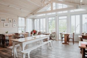 un comedor con mesas, sillas y ventanas en Le Lodge Kerisper, en La Trinité-sur-Mer