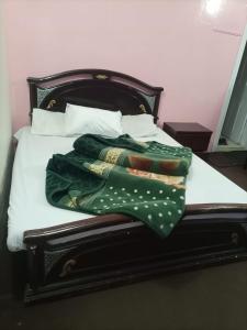 a bed with a green blanket and pillows on it at Kaghan Valley Hotel in Naran