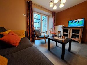 a living room with a couch and a tv and a table at D'un coin à l'autre in Nadrin