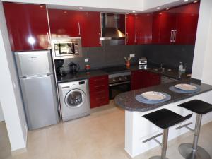 een keuken met rode kasten en een wasmachine en droger bij Ver-O-Mar in Carvoeiro