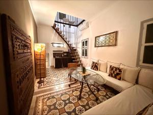 uma sala de estar com um sofá e uma mesa de vidro em Riad Home Zemrane em Marrakech