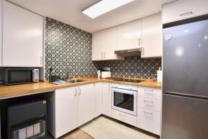 a kitchen with white cabinets and a stainless steel refrigerator at STAY Las Segadas in Oviedo