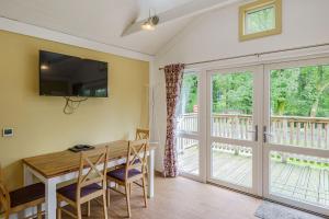 a dining room with a table and a balcony at Squirrel Lodge 41 with Hot Tub in Newton Stewart