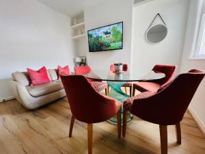 a dining room with a glass table and red chairs at Liverpool Peach House - 4 bedrooms in Liverpool