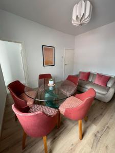 a living room with a glass table and red chairs at Liverpool Peach House - 4 bedrooms in Liverpool