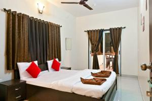 - une chambre avec un grand lit et des oreillers rouges dans l'établissement Ekant Villa Panchgani Mahabaleshwar, à Panchgani