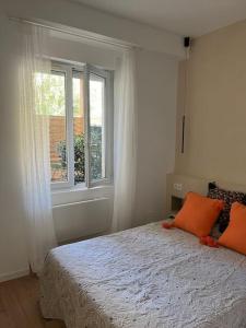 een slaapkamer met een bed met oranje kussens en een raam bij Petit cocon cosy in Bordeaux