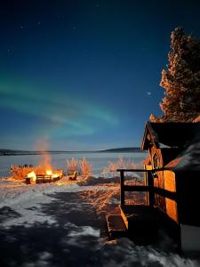 un foyer extérieur dans la neige la nuit dans l'établissement Camp Caroli Hobbit Hut, à Jukkasjärvi