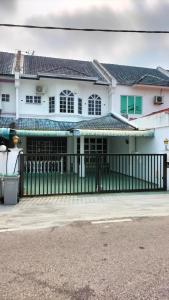 a white house with a green fence in front of it at Homestay No. 8 in Segamat