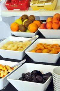 una mesa cubierta con tazones blancos llenos de frutas y hortalizas en Hotel Oliver, en Caorle