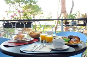 una mesa con una bandeja de alimentos para el desayuno y zumo de naranja en Hotel Oliver, en Caorle
