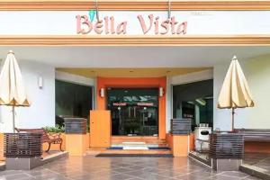 a hotel with chairs and umbrellas in front of a building at Eastiny Bella Vista Hotel in Pattaya