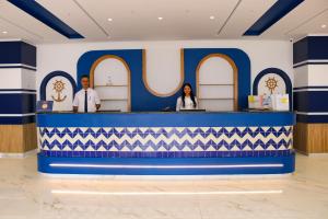 deux personnes debout à un comptoir en bleu et blanc dans l'établissement Marina Cap Monastir- Appart'Hôtel, à Monastir