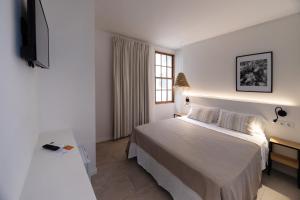 a white bedroom with a bed and a window at Tres Tocs in Ciutadella