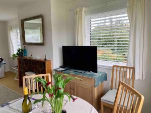 a living room with a television and a table with a dining room at Sea Breeze Wembury Beach in Wembury