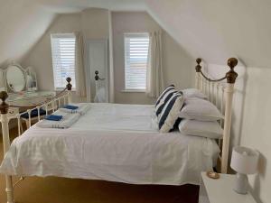 a bedroom with a white bed with pillows and a table at Sea Breeze Wembury Beach in Wembury