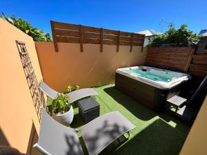 a small backyard with a hot tub and chairs at Nour Lumière d’Etoile in Saint-Pierre