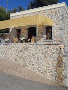 un bâtiment en pierre avec un parapluie jaune dans l'établissement Panos Renos Studio, a cozy home by the beach!, à Kalymnos