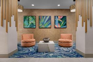 a lobby with two chairs and a table and paintings at Hyatt Place Orlando / I-Drive / Convention Center in Orlando