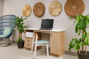 a desk with a computer and a chair and plants at Hyatt Place Orlando / I-Drive / Convention Center in Orlando