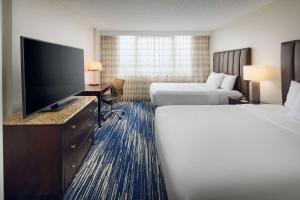 a hotel room with two beds and a flat screen tv at Embassy Suites by Hilton West Palm Beach Central in West Palm Beach